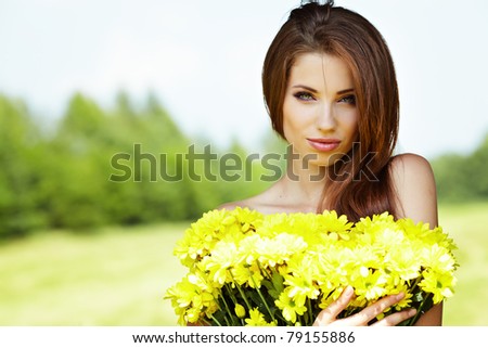 Closeup portrait of cute young girl with yellow flowers smiling outdoors