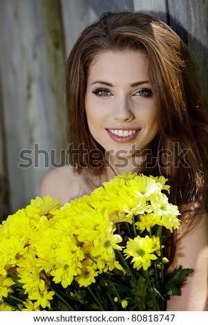 Closeup portrait of cute young girl with yellow flowers smiling outdoors