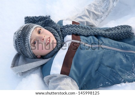 Young boy playing outside in the snow on a cold day