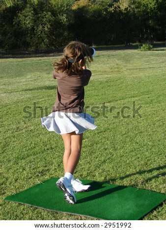 Young girl taking a shot during a golf lesson