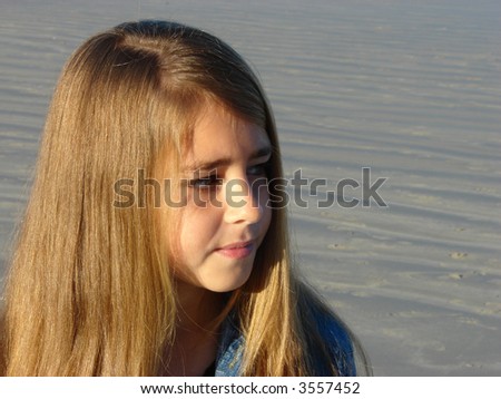 Young girl standing on the beach, looking into the distance