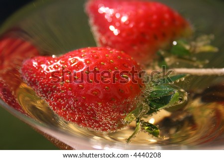 Two strawberries in a martini glass filled with sparkling apple juice
