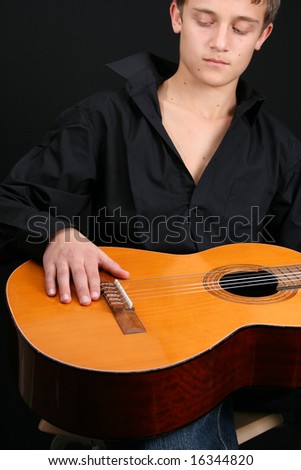 Teenage male in casual attire holding a guitar. FOCUS ON GUITAR by HAND