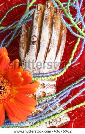 Wooden hand with beads and an orange flower