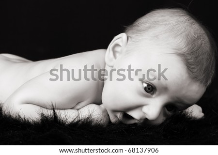 Beautiful three month old baby boy lying on black fur