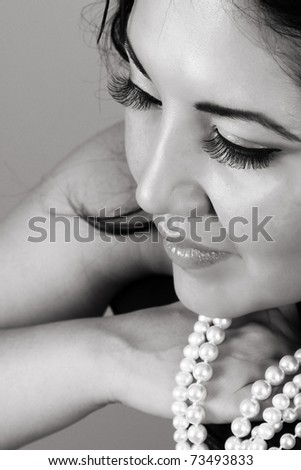 Beautiful brunette female leaning on chair back with pearls