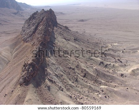 Aerial view of single conical mountain in desert.