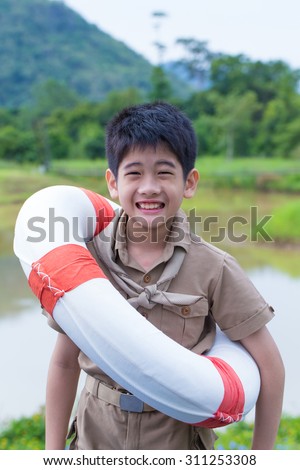 Asian boy scout, a cute Asian boy scout in uniform happy smile with lifebuoy by the river shore