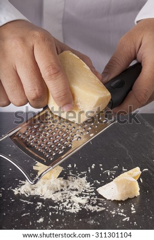 grated cheese, a chef hand grating parmesan cheese