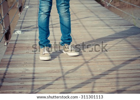 standing strong, abstract pose of a kid leg standing on a wood bridge with shadow lighting