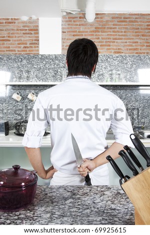 Murderer, Chef pose as a murderer, hide his knife at the back in the kitchen.