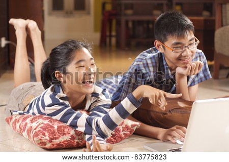 happy sibling, sister and brother laughing with game in computer notebook.