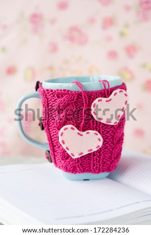Pink cup in a blue sweater with felt hearts