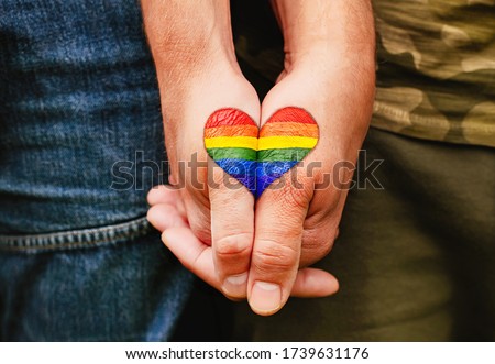 Rainbow heart drawing on hands, LGBTQ love symbol, gay couple hand in hand, lovers