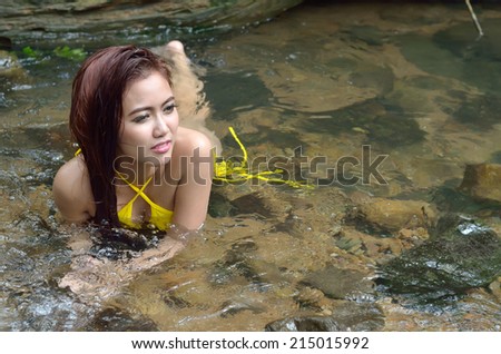 Beautiful slim fitness model posing sexy in front of waterfalls wearing bikini swimwear at summer time