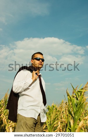 Business man in a corn field, watching the sky
