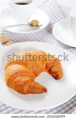Croissant on a plate with coffee. Traditional French breakfast