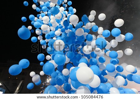 blue and white balloons flying up in the dark sky