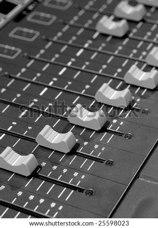 Faders of a studio soundboard.  Black and white image scanned from medium format film. Film grain visible.