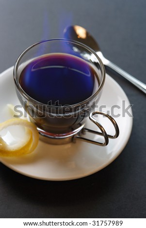 An image of a Carajillo - Spanish drink combining coffee with brandy or rum.  Set aflame to heat the coffee, sugar and liquor. Selective focus - focus is on the rim of the glass.
