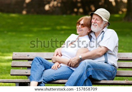 Senior couple sitting on a park bench hugged, shallow depth of field