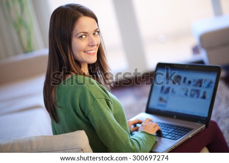Beautiful young woman using laptop, browsing some photos