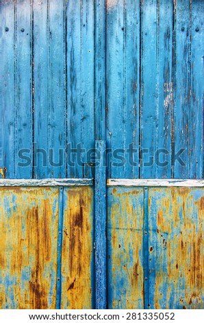 Detail of an old wooden door with scratched blue and yellow paint