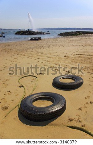 Two tires buried in the sand and a geyser in the water