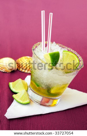 Brazilian caipirinha cocktail with limes and sea-shells on a side