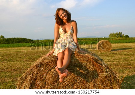 Young woman having fun on the field with hay bale rolls