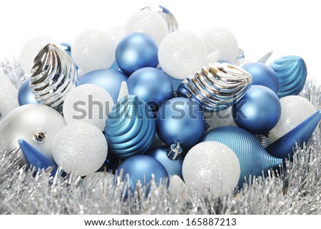 Close-up image of silver, white and blue Christmas bulbs on a bed a tinsel garland.  On a white background.