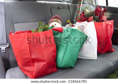 The back seat of a car with four bags of Christmas gifts and decor.