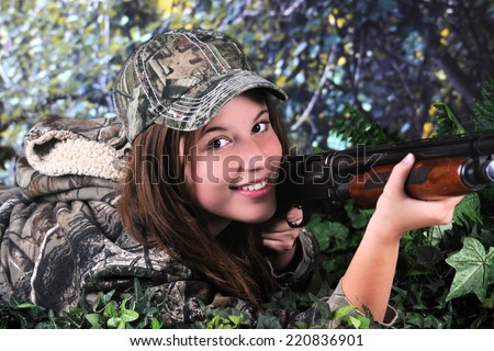 Close-up image of a pretty young teen hunter looking at the viewer as she lays on the ground ready to hit her prey.