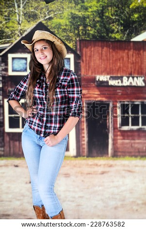 A pretty young teen happily standing in the main street of an old western town.