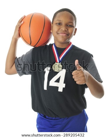 A happy preteen athlete supporting his basketball on his shoulder, a thumbs up with the other hand and a red, white and blue winning ribbon and metal around his neck.  On a white background.