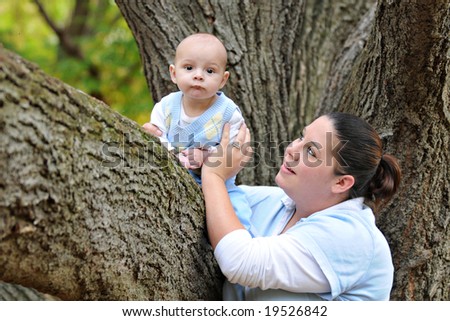 Mom securing her baby has he sits in his first tree.