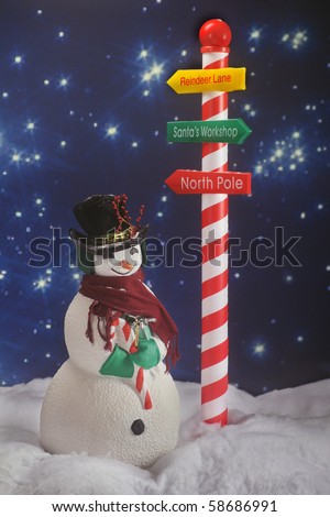 A snowman in the snow beneath a Santa sign on a long, starry North Pole night.  Intentionally dark for nighttime lighting.