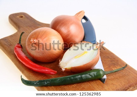 Three onions, two peppers, kitchen knife, cutting board. Onions cut. Red and green peppers