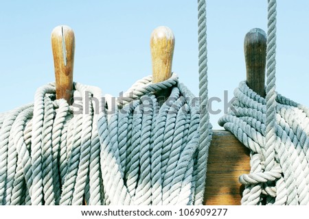 Detail of vintage wooden tools and ropes of a boat with blue light sky on the background