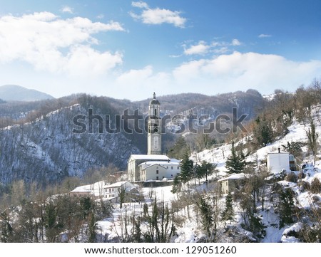 Wonderful view of mountains and a church isolated with snow and blue sky with clouds