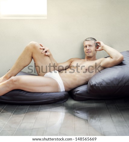 Handsome young male model lying in underwear on pillows