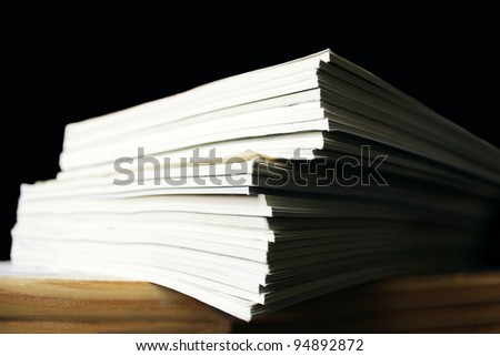 Photo of many magazines stacked on one another on the table, in the black background
