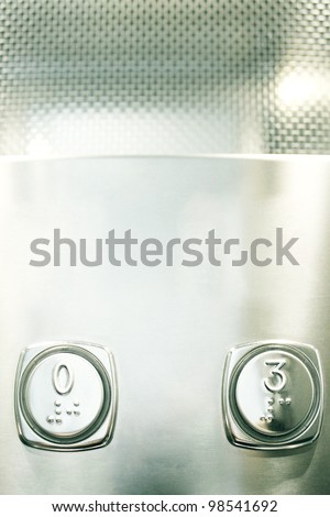 Detail of two buttons of the numbers zero and three of an elevator with braille write