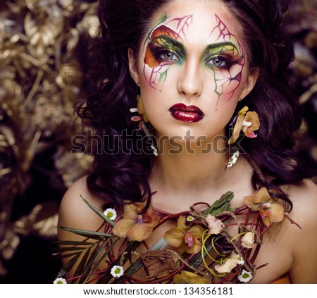 beauty woman with face art and jewelry from flowers orchids