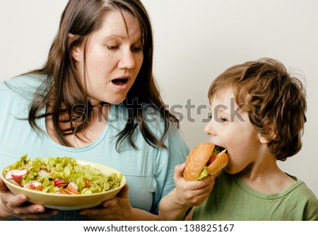 fat woman holding salad and little cute boy with hamburger
