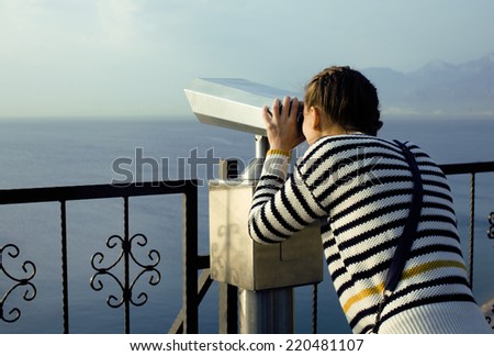 young woman looking through telescope at sea viewpoint in Ataturk park, sunny morning