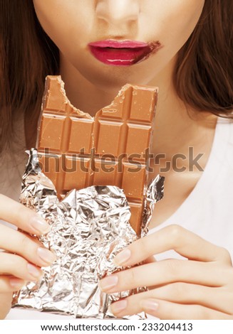 close up portrait  brunette girl with bar of chocolate, dirty mouth on white