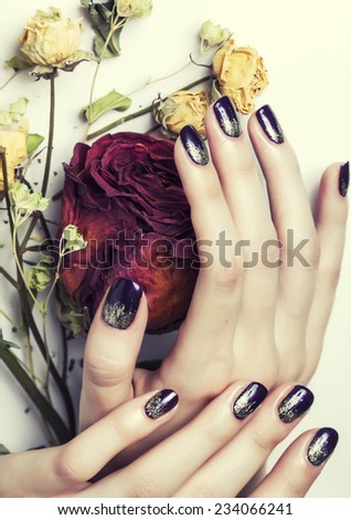 close up picture of manicure nails with dry flower red rose, dehydrated by winter
