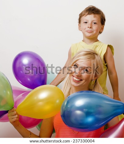pretty family with color balloons on white background, young blond woman with little boy on birthday party