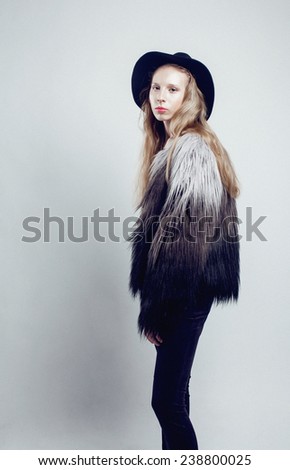 young blonde teenage girl in hat and fur coat, fashion dressed  model, studio shot